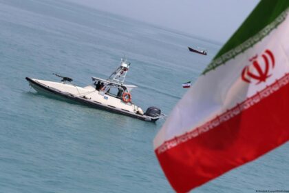 Imagen de un buque de guerra en el estrecho de Ormuz, con la bandera de Irán en el fondo
