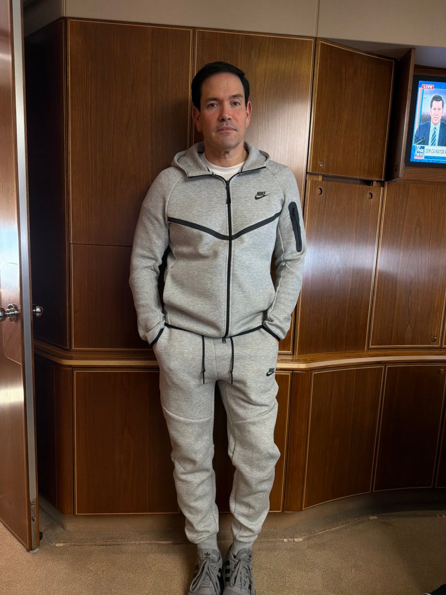 Marco Rubio sonriendo en el Air Force One con una sudadera gris Nike Tech Fleece