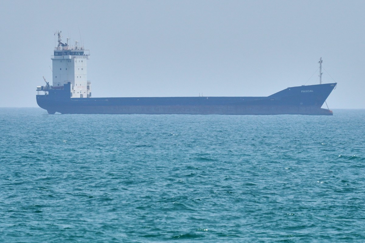 Buques mercantes navegando el estrecho de Ormuz bajo un cielo tenso y nubes de conflicto geopolítico