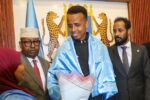 Omar Ardan, el árbitro somalí, sonriendo y sosteniendo la bandera de Somalia