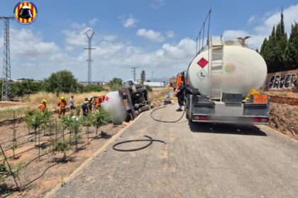 Un camión cisterna volcado en una vía de servicio con un gran escape de combustible
