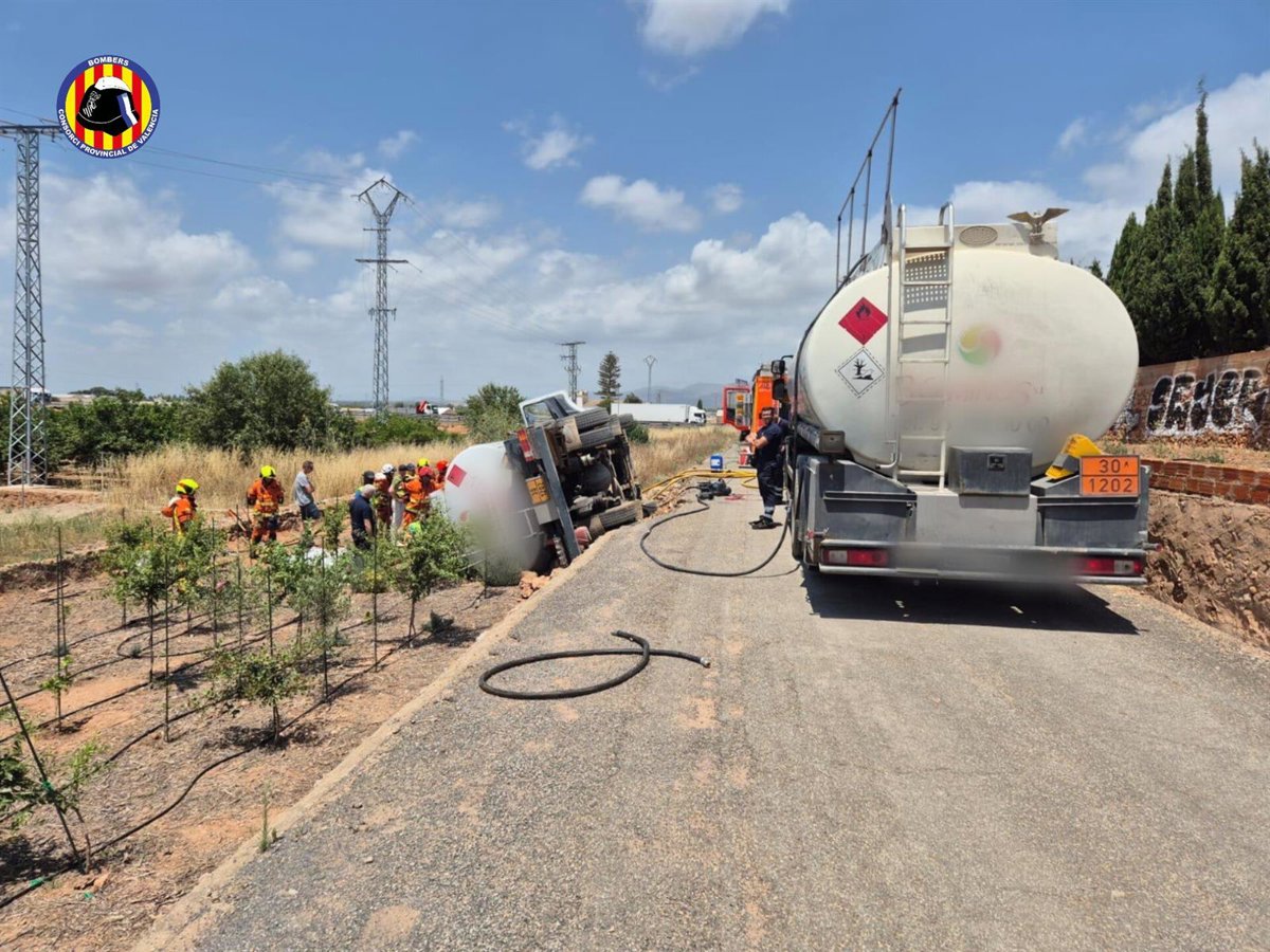 Un camión cisterna volcado en una vía de servicio con un gran escape de combustible