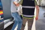 Imagen de un agente de policía llevando a un detenido, colombiano reclamado por Interpol