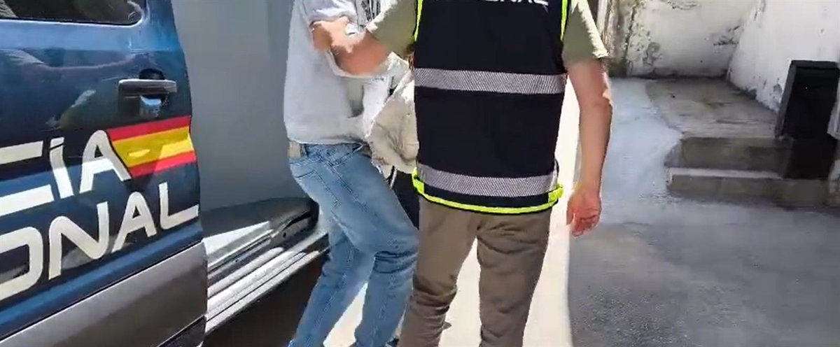 Imagen de un agente de policía llevando a un detenido, colombiano reclamado por Interpol